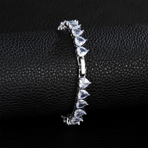 Macro detail of silver tennis chain with heart-shaped cubic zirconia on black stand