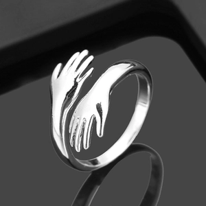 Dettaglio macro dell'anello abbraccio argento con finitura lucida su fondo riflettente