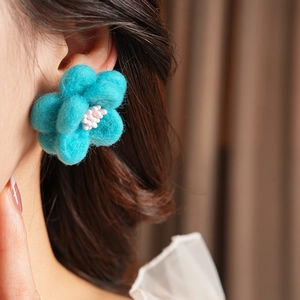 Gros plan sur boucle d'oreille fleur en feutre bleu avec texture détaillée