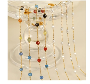 Detail view of gold chain jewelry with multi-color gemstones and white pearls