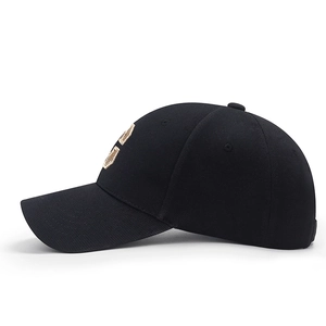 Black cotton canvas baseball cap with gold embroidery and curved brim in a side view