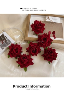 Close-up of red velvet rose hairpins with green leaves on silk background with pearls