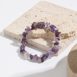 Detail view of purple natural stone elastic bracelet on a beige travertine decorative board