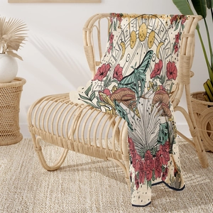 Detail of artistic flannel blanket with luna moth and mushroom on a rattan chair