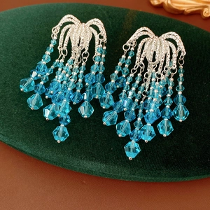Detail shot of silver leaf-style earrings with cascading blue crystal beaded tassels