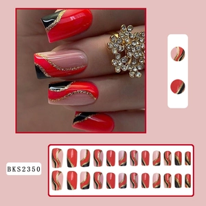 Detail view of red and black press-on nails with golden glitter wave accents