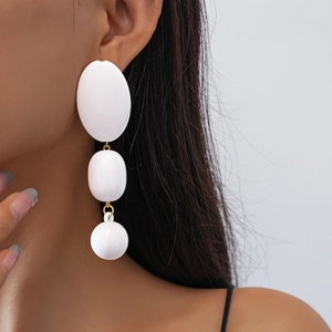 Détail de grandes boucles d'oreilles géométriques en acrylique blanc avec pendentif ovale