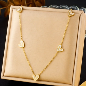 Gold-plated stainless steel necklace featuring five white shell heart charms on display