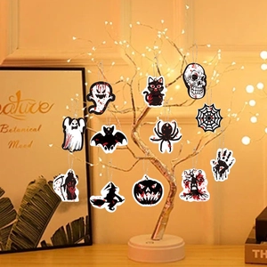 Set of 12 Halloween hanging ornaments with ghost and pumpkin designs on a lit tree