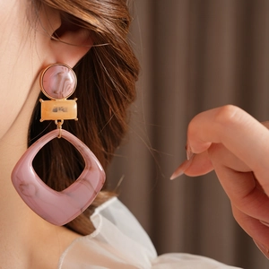 Detail view of stylish resin geometric earrings with marble texture on female model