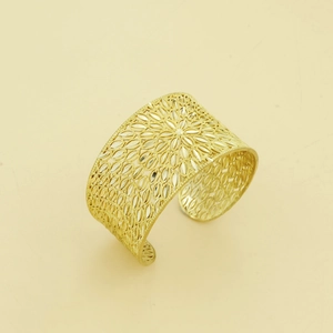 Detailed close-up of wide hollowed-out gold cuff bracelet with intricate floral patterns