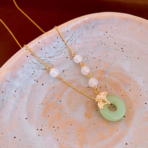 Détail du collier feuille de ginkgo avec pendentif en jade et perles œil-de-chat