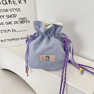 Dettaglio borsa a secchiello vichy blu con toppa cartoon e lacci colorati con perline
