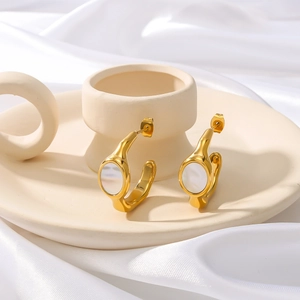 Vintage gold irregular C-shape earrings with white shell inlays on white silk background