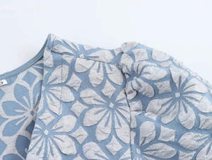 Detail von blauem und silbernem Jacquard-Stoff am V-Ausschnitt des Kleides