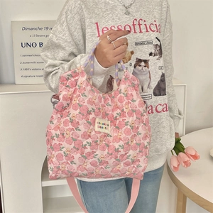 Detail of pink floral quilted handbag showing fabric texture and adjustable shoulder strap