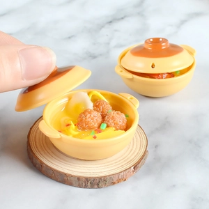 Macro detail of miniature yellow clay pot noodles with realistic resin food ingredients
