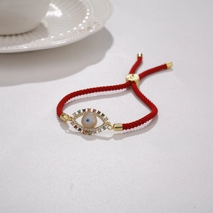 Close-up of red braided evil eye bracelet with colorful cubic zirconia and gold frame
