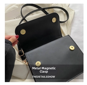 Detail shot of the dual magnetic gold snaps on a black leather handbag closure