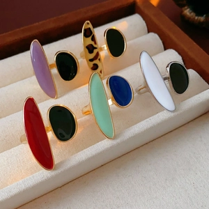 Detailed display of colorful enamel drop rings in various patterns on a velvet box