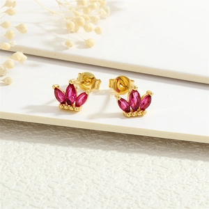 Detailed macro view of gold-plated crown earrings with marquise-cut ruby zircons