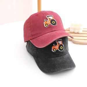 Detail of two washed cotton baseball caps with embroidered tractor patches and curved brims