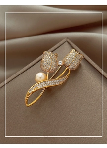 Close-up of elegant gold tulip brooch with sparkling pavé crystals and white pearl