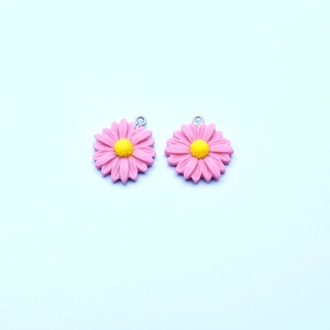 Detailed macro view of two pink daisy flower resin charms with silver metal rings