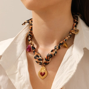 Detailed view of leopard print silk scarf necklace with golden heart and skull charms
