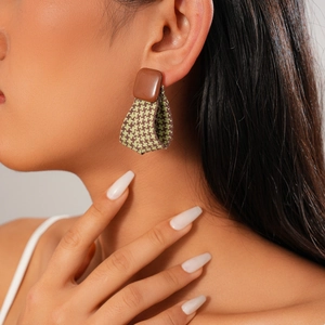 Detail of vintage earring featuring brown resin and green houndstooth fabric texture