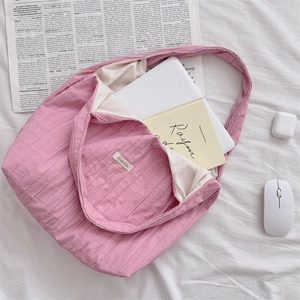 Detail of pink corduroy shoulder bag showing fabric texture and large inner capacity