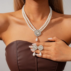 Close-up of double layer pearl necklace and rhinestone drop earrings on female model