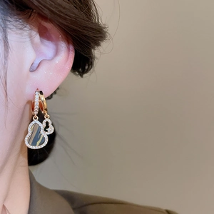 Close-up of gold double wulu drop earrings with pave diamonds on model's ear
