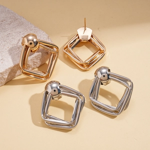 Close-up of geometric layered square stud earrings in polished gold and silver finishes