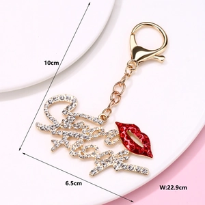 Detail of golden alloy crown keychain with red lips and sparkling rhinestones