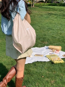 Floral canvas tote bag with drawstring closure shown in an outdoor park picnic setting