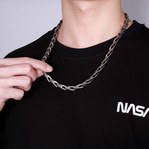 Détail d'un collier en acier inoxydable à maillons torsadés porté sur un t-shirt noir