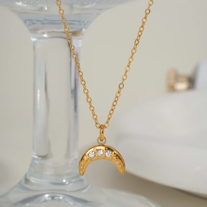 Close-up of golden moon pendant necklace featuring three sparkling zircon crystal accents