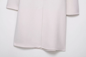 Detail of wool blend coat hem featuring a neat back split design and fine fabric texture