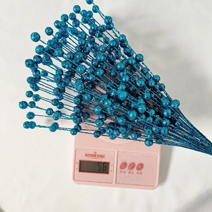 Close-up of glittery blue decorative berry stems weighing 56 grams on a scale