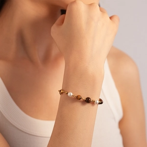 Détail d'un bracelet en perles et pierres œil de tigre sur le poignet d'une femme