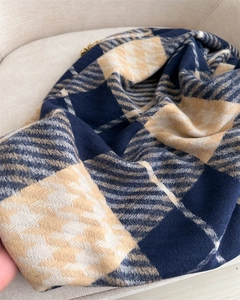 Nahaufnahme der weichen karierten Schal-Textur in Marine und Beige auf einem Stuhl