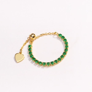 Close-up of adjustable gold chain ring with green zircon stones and heart charm