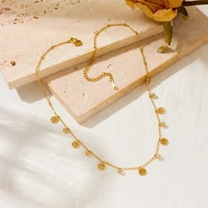 Collier Arbre de Vie doré avec cristaux posé sur une surface en pierre texturée