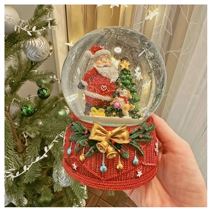 Close-up of snow globe featuring Santa and Christmas tree with a festive warm background