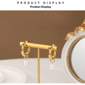 Detailed shot of golden baroque hoop earrings with white pearl drops on a T-stand