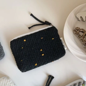 Dettaglio della pochette in maglia nera a pois gialli con etichetta simple wish