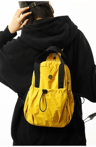Detail of yellow nylon backpack featuring natural crinkle texture and black strap accents