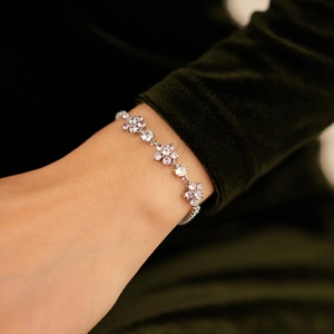 Close-up of a silver flower bracelet with pink zircons worn on a model's wrist