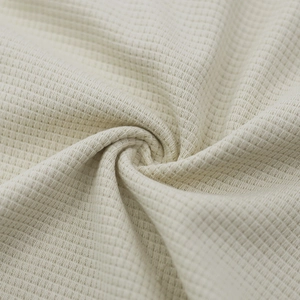 Macro shot of off-white waffle knit fabric texture showing softness and drape
